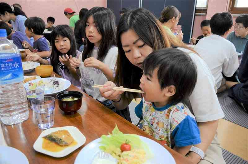 岩手県産の食品が寄付された子ども食堂で食事する親子連れ＝大津町