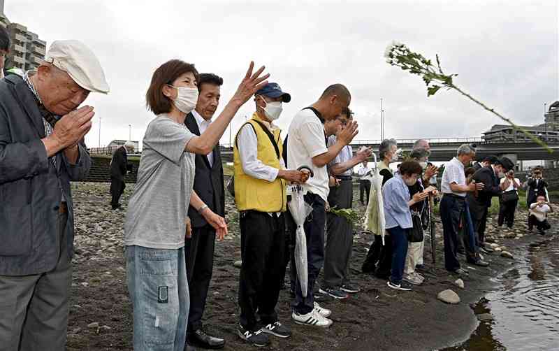 「6・26水害」の慰霊祭の後、白川に菊を投げ入れ、犠牲者を悼む地元住民ら＝26日午前、熊本市中央区（石本智）