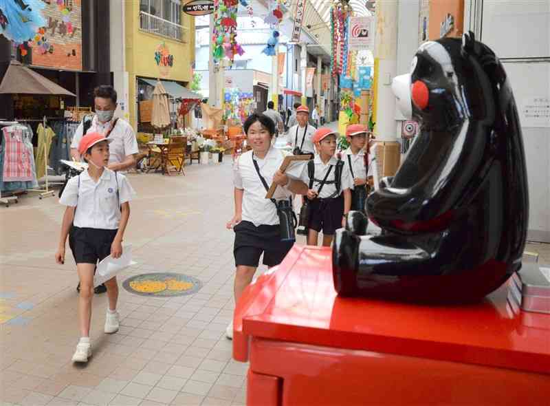 本町商店街にある「くまモン像」を探す南方小の児童ら＝八代市