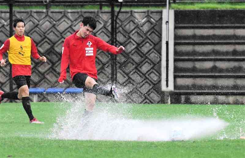 東京V戦に向けた練習に取り組むロアッソ熊本のMF平川怜（右）。大雨の中、ボールをけった足元から水しぶきが上がった＝県民総合運動公園ラグビー場