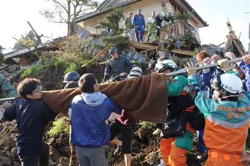 南阿蘇村の黒川地区で倒壊した家屋から住人を救出する消防隊と東海大阿蘇キャンパスの学生ら＝2016年４月16日午前７時半ごろ