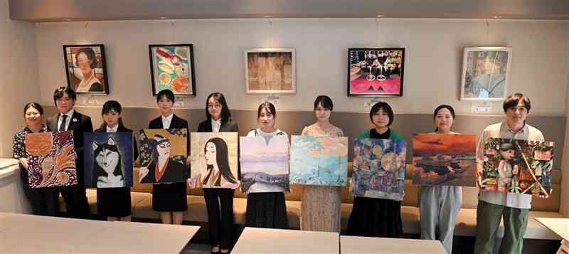 新たに飾られた作品（後ろ）と展示を終えた作品を手にする学生たち＝熊本市中央区