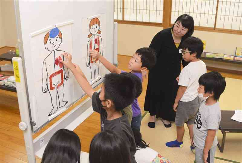 ワークショップで体の仕組みを学ぶ子どもたち＝熊本市中央区