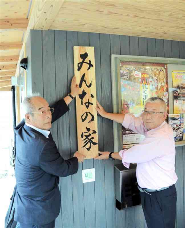 中津道地区に完成した「みんなの家」に表札を取り付ける住民の蓑田陽一さん（左）と山口芳幸さん＝1日、八代市