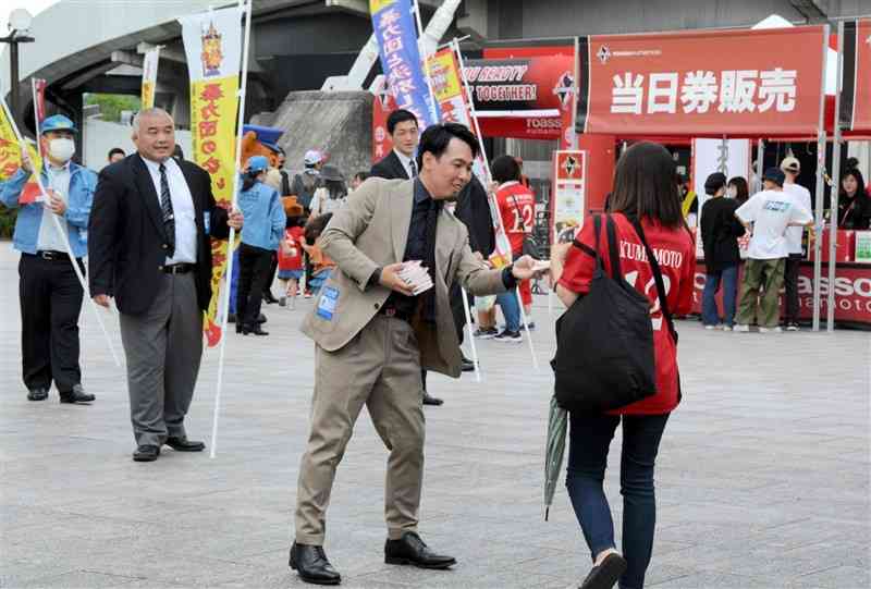 ロアッソ熊本のサポーター（写真手前右）に暴力団排除への協力を呼びかける県警の捜査員ら＝2日、熊本市東区