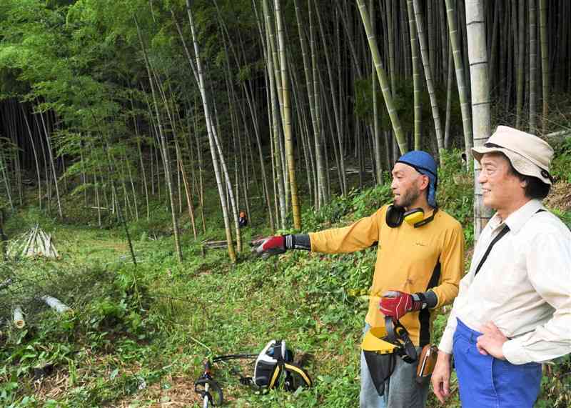 竹林整備について移住者の男性と打ち合わせをする下中地区の野中裕二区長（右）＝山鹿市