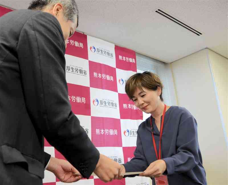 新田峰雄熊本労働局長（左）から諮問書を受け取る熊本地方最低賃金審議会の倉田賀世会長＝5日、熊本市西区