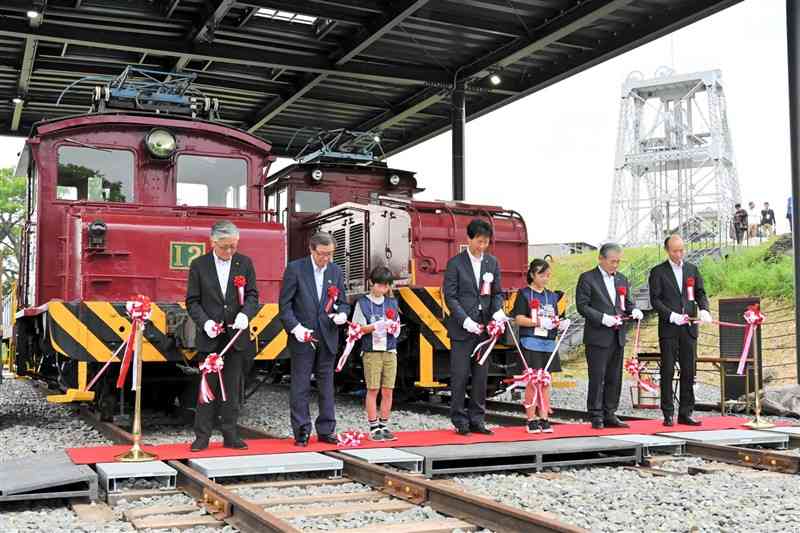 車両の前でテープカットする関係者＝荒尾市