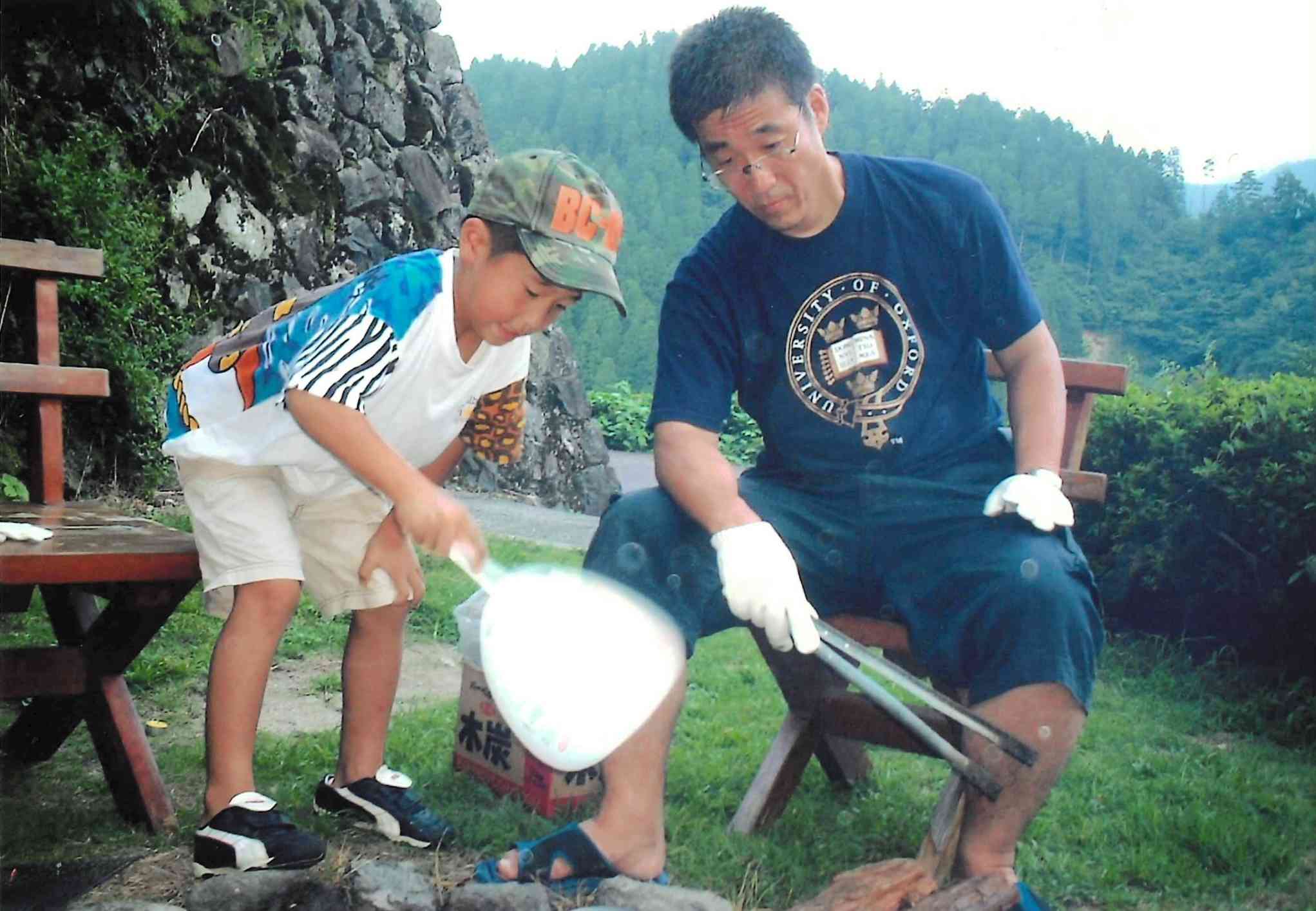 鯛生金山キャンプ場で長男・慧さん（左）と火をおこす筆者＝大分県日田市