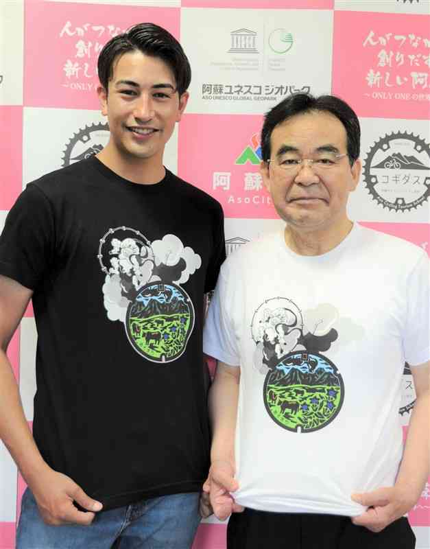 阿蘇市のマンホールのふたがデザインされたTシャツを試着する佐藤義興市長（右）と足立拓海さん＝同市