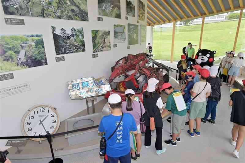 熊本地震震災ミュージアムの中核拠点「KIOKU」に展示された、つぶれた車などを見学する地元の小学生たち＝南阿蘇村（上杉勇太）