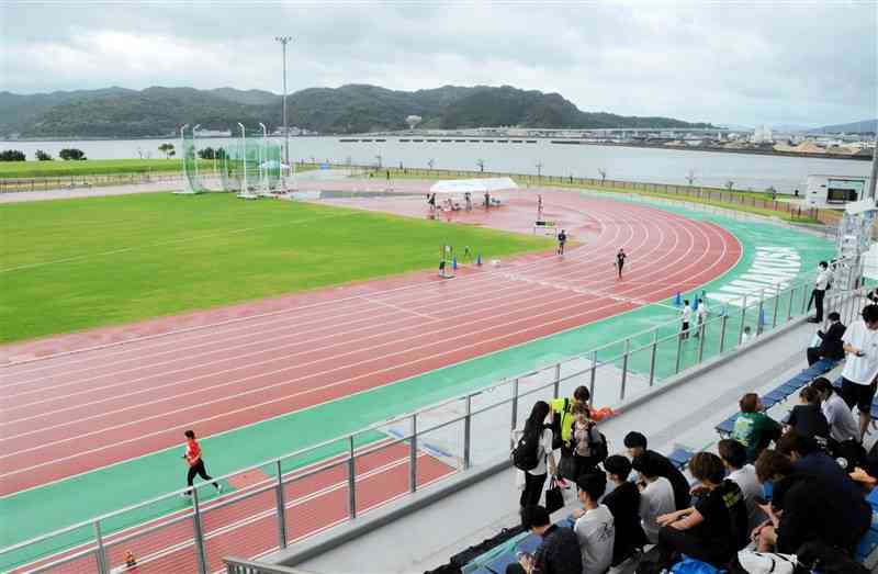 天草市陸上競技場（あましんスタジアム）の全天候型400メートルトラック。奥は本渡港と天草未来大橋＝15日、同市