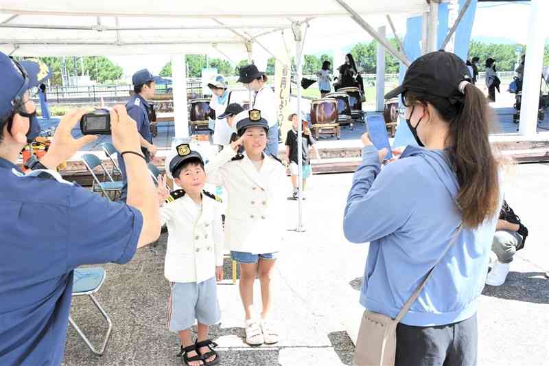 「熊本港フェスティバル」で海上保安庁の制服を試着してポーズを取る子どもたち＝17日、熊本市西区