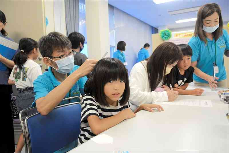 国立水俣病総合研究センターのオープンラボで、毛髪の水銀測定を受ける小学生＝水俣市