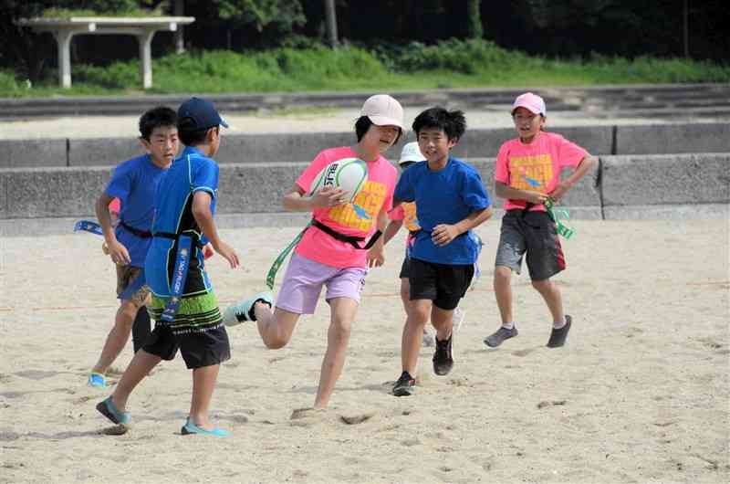 天草ビーチラグビー大会で元気いっぱいプレーする子どもたち＝天草市