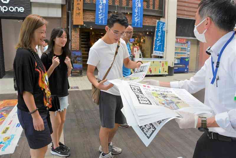 東海大星翔の甲子園出場決定を伝える号外を受け取る男性ら＝24日、熊本市中央区