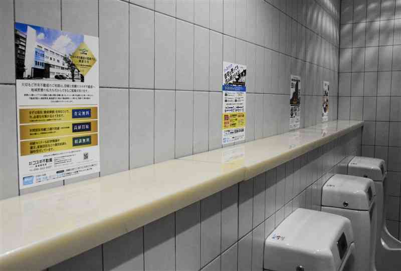 県庁本館1階の男子トイレに掲示されている広告。10月から別の階のトイレなどにも掲示スペースを増やす＝28日、熊本市中央区