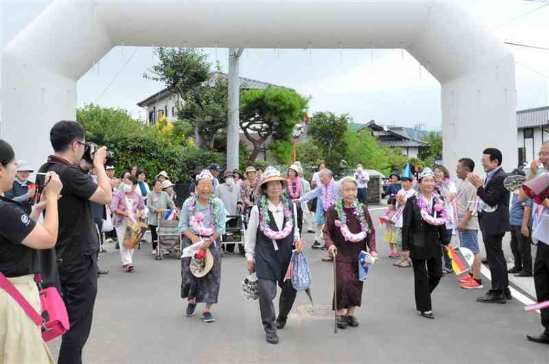 町道と避難路の整備完了を祝う「開通式」で笑顔で歩く住民たち＝30日、益城町
