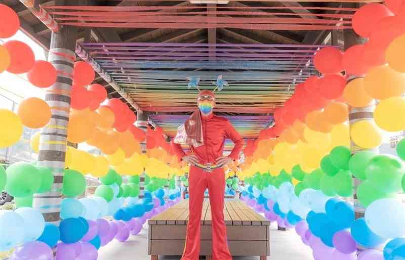 ことし3月、道の駅小国ゆうステーションでのワークショップ作品「みんなでつくる虹色の風景」の中に立つレインボー岡山さんⓒHiroshi　Sugahara（作家提供）