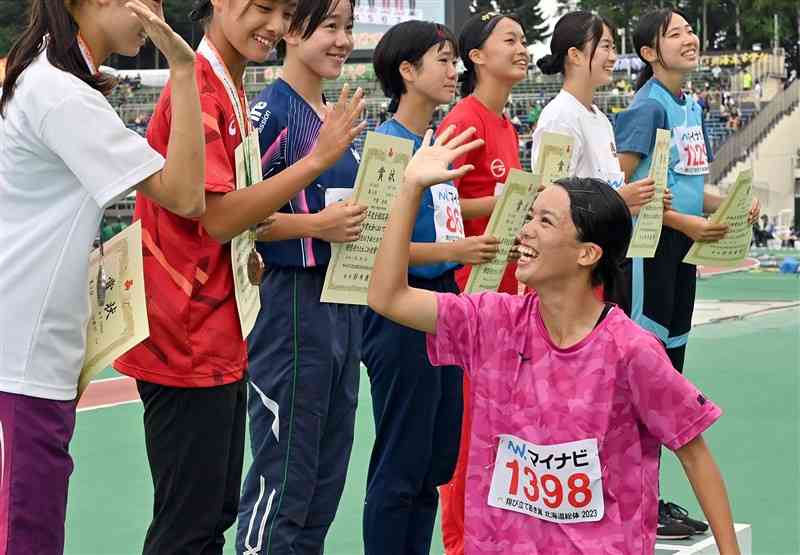 陸上女子100メートルで優勝し、表彰台に上がる前にハイタッチして健闘をたたえ合う山形愛羽（右手前、熊本中央）＝3日、札幌市厚別公園競技場（上杉勇太）