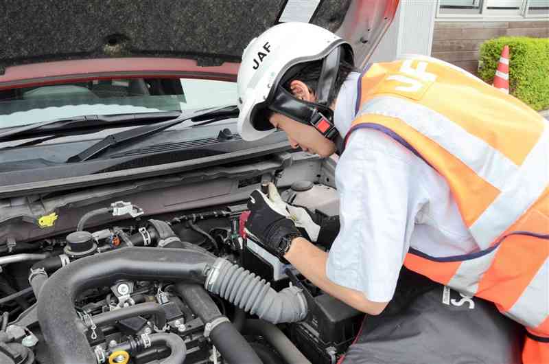 車のバッテリーを点検するJAF熊本支部の隊員。夏場の長距離運転を前に万全な準備を呼びかける＝熊本市東区