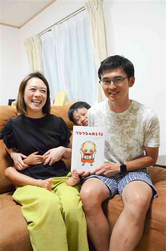 絵本「つるつるのおとうと」を出版した森さん家族。次男は母親の亜希子さんの背中に隠れている＝熊本市北区