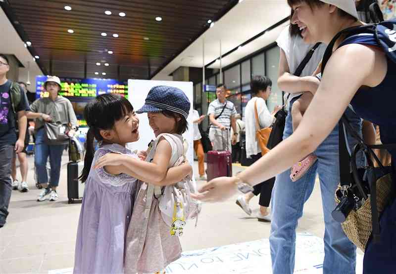 他県から帰省し、出迎えたいとこ（手前左）と抱き合う子ども＝11日午前10時10分ごろ、熊本市西区のJR熊本駅（小野宏明）