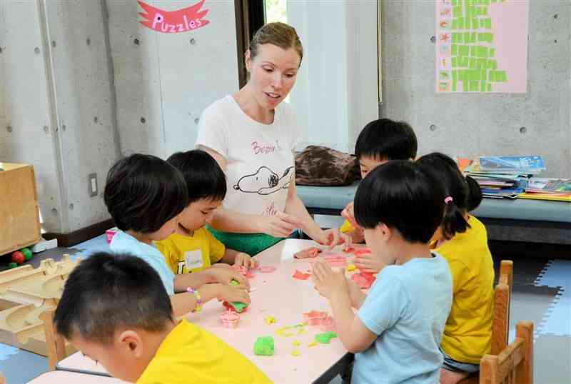 サマースクールの幼児クラスで、外国人講師に教えてもらいながら紙粘土で海の生物を作る子どもたち＝熊本市中央区