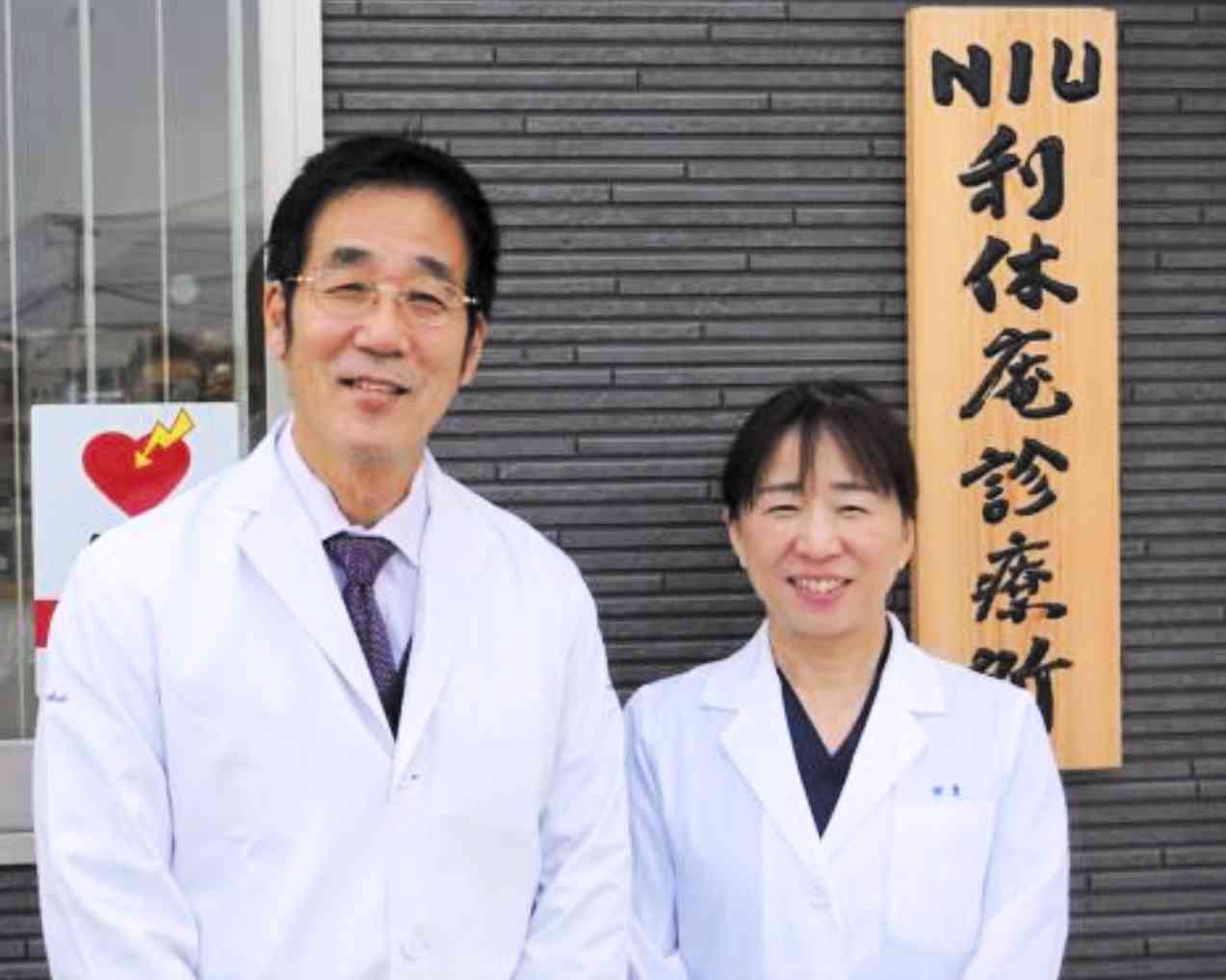 学内に開設した診療所はコンテナで始まったが、1年後、立派な建物になった。筆者（左）と妻恵子さん＝2022年8月、長崎国際大