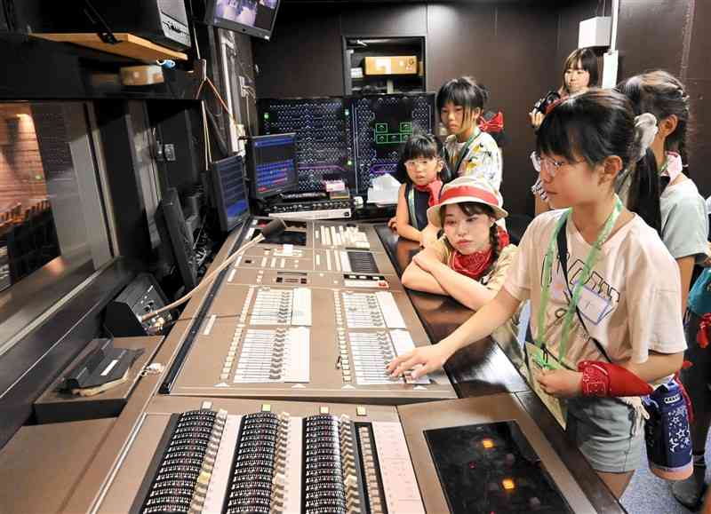調光室で機器を操作し、舞台に照明を当てる小学生＝熊本市中央区