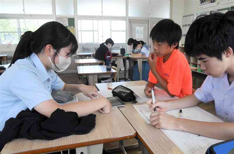 城北高の生徒（左）に数学の問題の解き方を習う米野岳中の生徒＝山鹿市