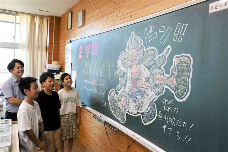 黒板アートを見て笑顔を浮かべる日吉東小の児童と、成清健太朗教諭（左）＝29日、同小