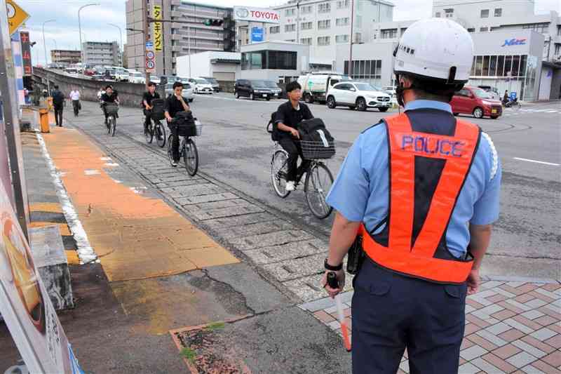 自転車利用者の交通違反を取り締まる熊本南署員（右）＝1日、熊本市中央区