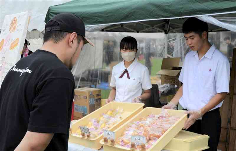 ジェーンズにゆかりのある野菜を使ったパンを販売する熊本商高の生徒＝熊本市中央区