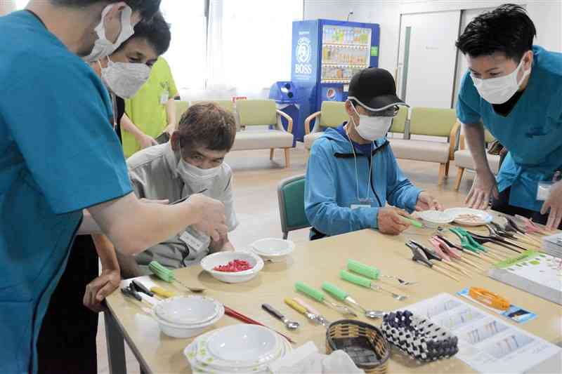 握りやすいように作られた箸やスプーン、フォークを試す参加者＝熊本市北区