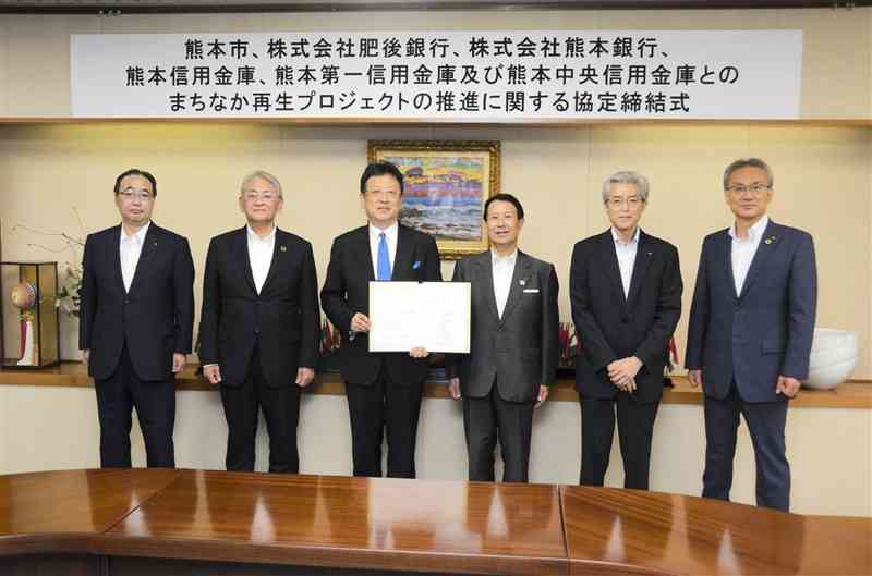 中心市街地のビル建て替え促進に向け、協定を結んだ熊本市の大西一史市長（左から3人目）と県内5金融機関のトップ＝5日、市役所