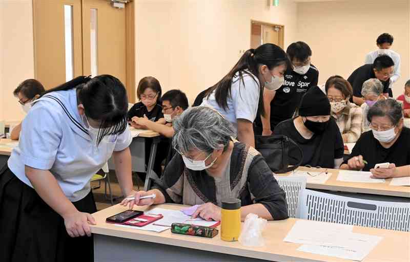 高校生らから会員登録の方法を学ぶ参加者たち＝菊池市