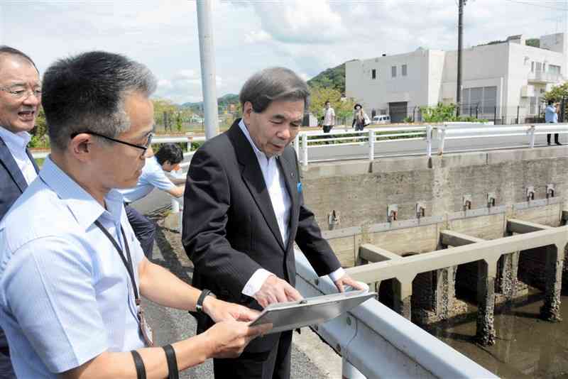 樋門の取り外しが完了した百間排水口を視察する蒲島郁夫知事（右）＝12日、水俣市