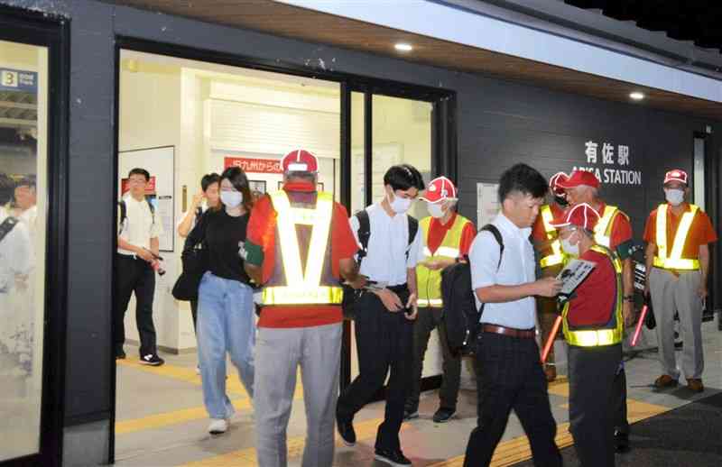 JR有佐駅で防犯啓発チラシを配る鏡地区防犯パトロール隊員や少年補導員ら＝八代市