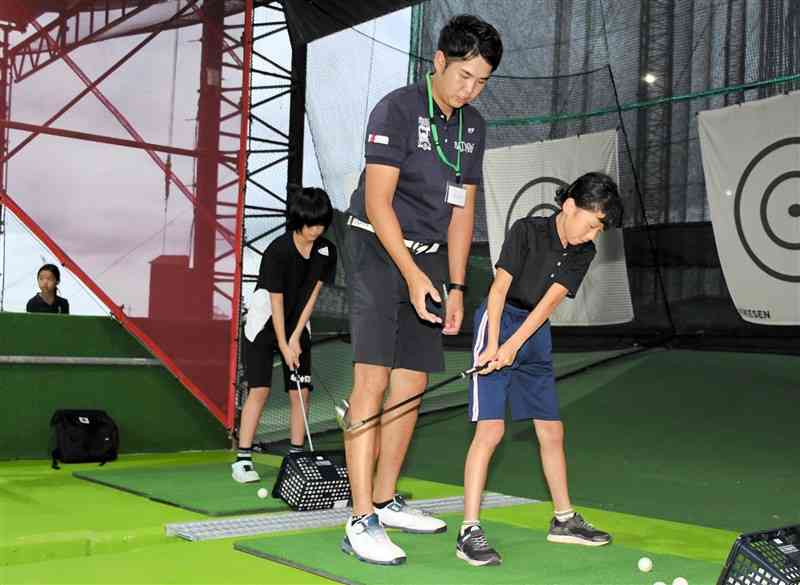 プロからスイングの指導を受ける「熊日ジュニアゴルフプロジェクト」の児童ら＝熊本市南区