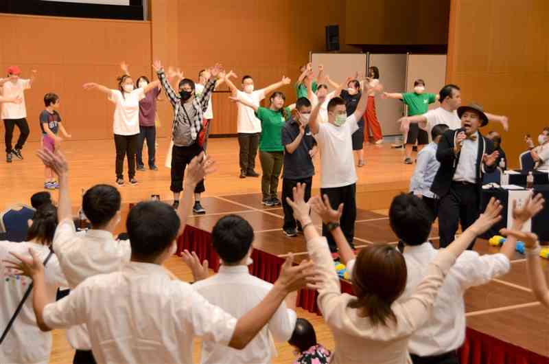 日本ダウン症協会熊本支部の50周年記念式典のエンディングで、テーマソングを歌い、盛り上がる参加者＝7月、熊本市中央区