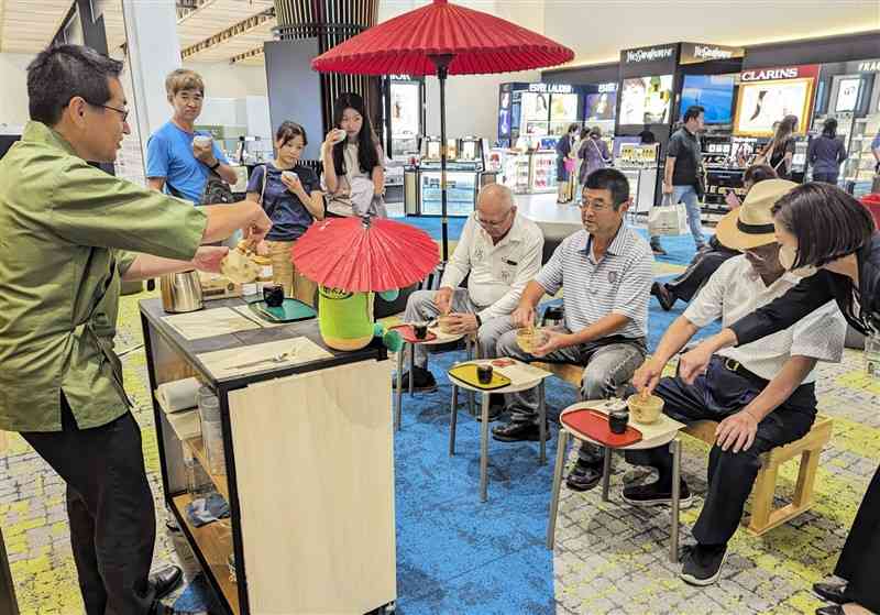熊本空港の免税店で抹茶をたてる台湾からの観光客ら＝益城町