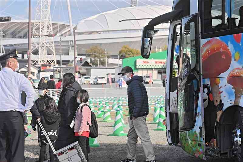 実証事業でパークアンドバスライドのシャトルバスを利用し、県民総合運動公園内の「えがお健康スタジアム」（奥）へ向かう観客＝2月、熊本市東区（谷川剛）