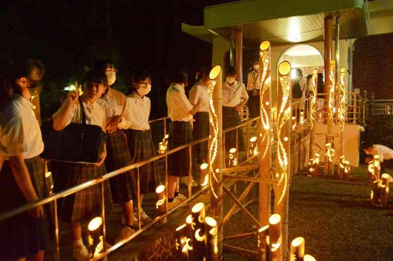 菊池恵楓園の納骨堂（右奥）周辺にともされた竹あかり＝29日夜、合志市