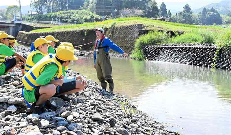 免田川と谷水川の合流地点で県職員の説明を聞く上小の児童たち＝あさぎり町