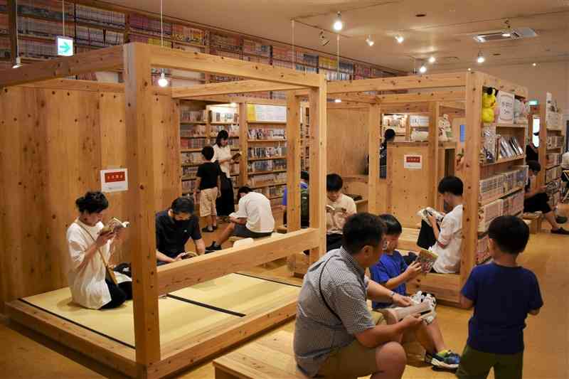 思い思いの姿勢でマンガを読む入館者たち＝合志市の合志マンガミュージアム