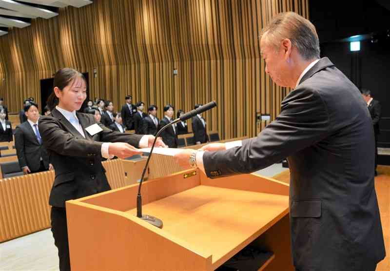 肥後銀行の内定式で、山木仁副頭取（右）から内定者を代表して通知書を受け取る女子学生＝2日、熊本市中央区