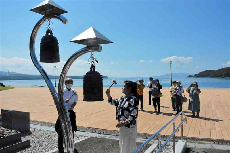 水俣病慰霊の碑の鐘を鳴らす福島の市民団体のメンバーら＝9月30日、水俣市の水俣湾埋め立て地