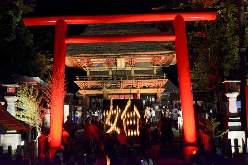青井阿蘇神社の楼門前に浮かび上がった竹灯籠による「始」の火文字＝人吉市