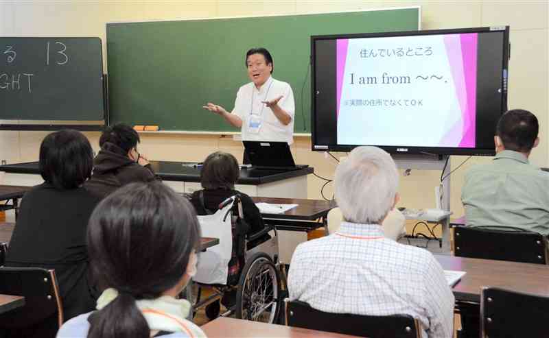 ゆうあい中の体験授業会で、英語による自己紹介の仕方を学ぶ参加者たち＝4日夜、熊本市中央区